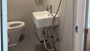 A compact bathroom with a toilet, sink, and shower. - Sounds Inn (Seoul)