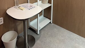 A small, private bathroom with a white sink, a mirror, a towel rack, a shelf with toiletries, and a trash bin. - Sounds Inn (Seoul)