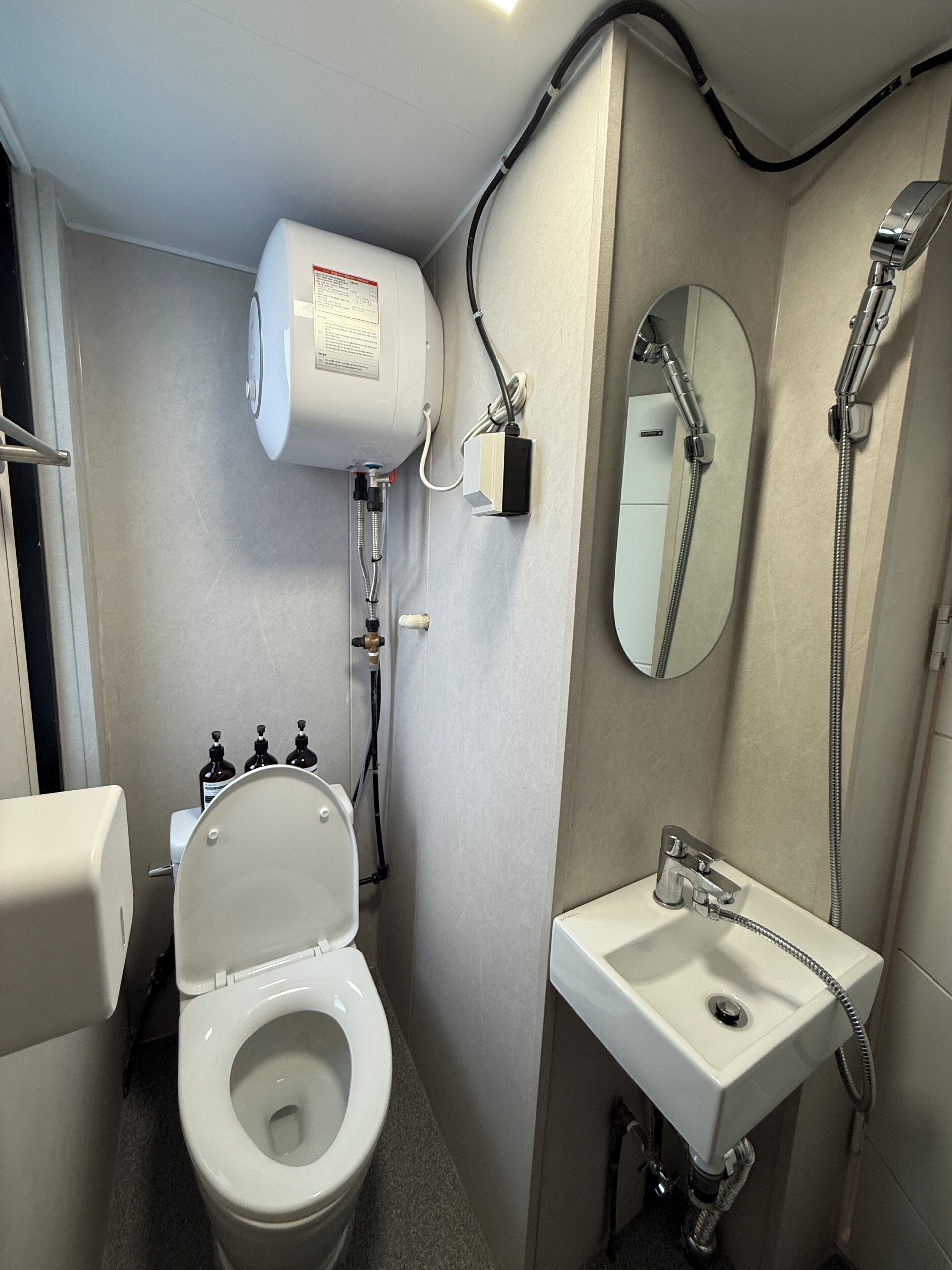 Un baño pequeño con inodoro, lavamanos, espejo y ducha.