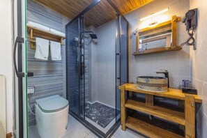 Une petite salle de bain dotée d’une douche à parois de verre, d’un meuble-lavabo en bois et d’un porte-serviettes.