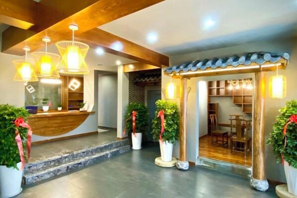 A hotel reception area with a wooden reception desk, potted plants, and a seating area with tables and chairs. - Shennongjia Nsnshan Youran Hotel (Shennongjia)