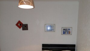 A bedroom with a bed, a hanging lamp, and two framed pictures on the wall. - Apartment Trocadero (Paris)