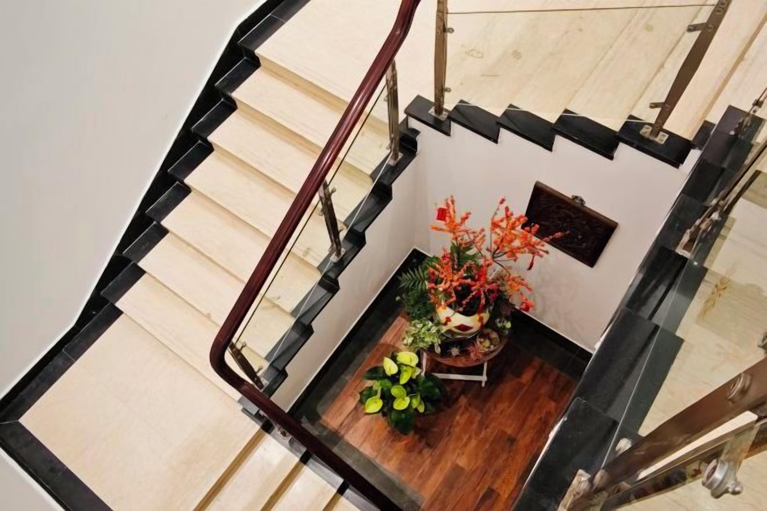 A staircase with a black railing, wooden steps, and a small indoor garden with plants and flowers.