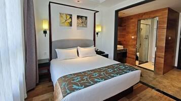 A hotel room with a large bed, a wooden floor, a mirror, and a wooden wall panel.