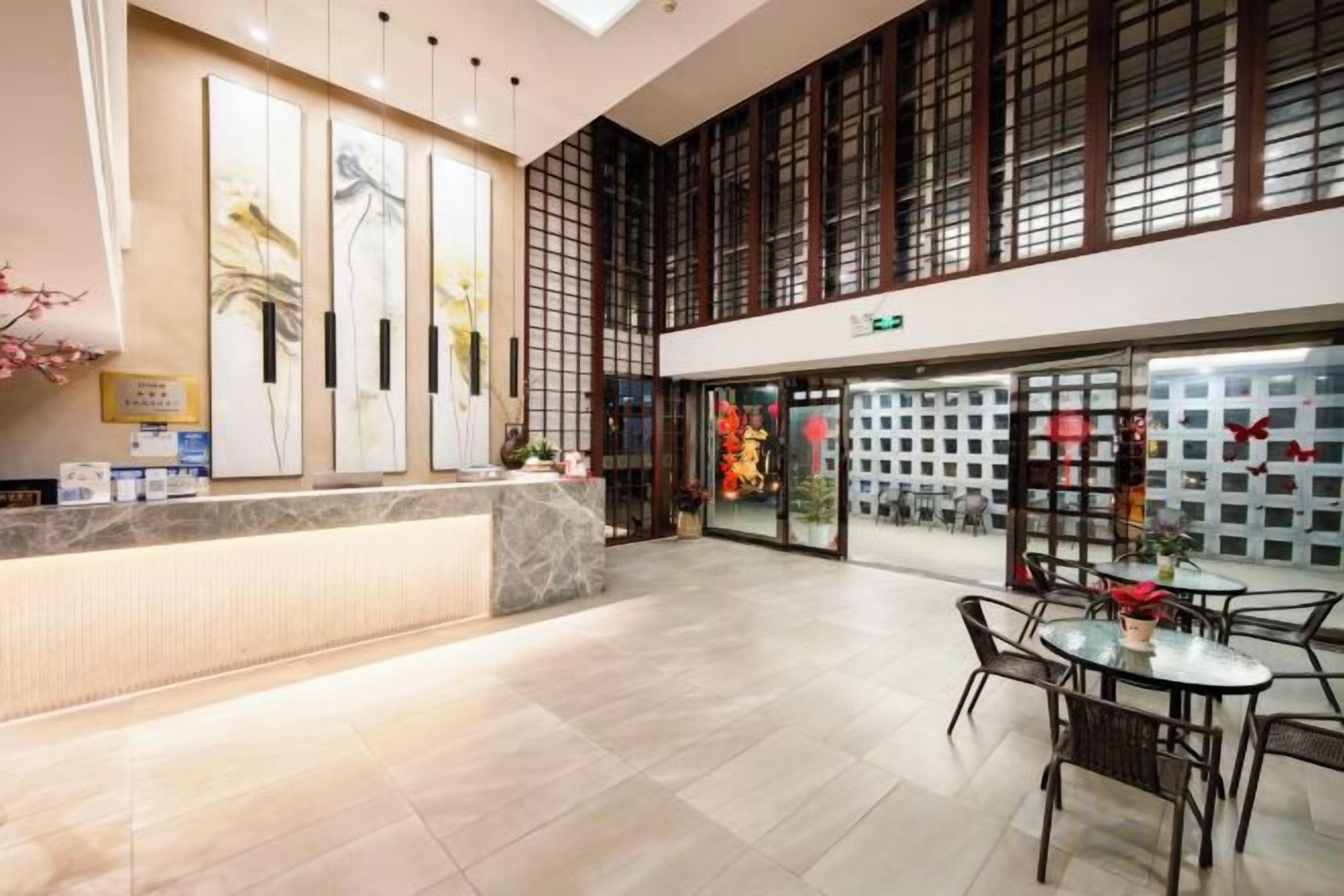 Un hall de hotel con mostrador de recepción, zona de estar y grandes ventanales.