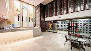 Un hall de hotel con mostrador de recepción, zona de estar y grandes ventanales.
