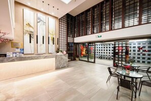 A hotel lobby with a reception desk, seating area, and large windows. - Baolong Yugang Hotel (Shanghai)