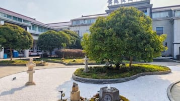 A courtyard with a large tree, a stone lantern, and a fountain.