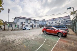 A parking lot with cars, a basketball court, and residential buildings in the background. - Baolong Yugang Hotel (Shanghai)