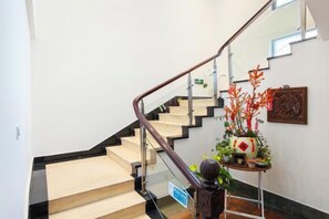 A staircase with a handrail, a potted plant, and a wall-mounted sign. - Baolong Yugang Hotel (Shanghai)