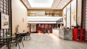 Un hall d’hôtel comprenant un comptoir d’accueil, un espace salon et un mur décoratif.