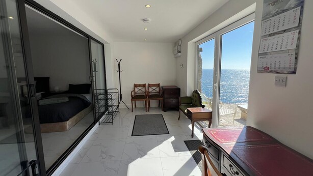 Une chambre moderne équipée d’un lit, d’un bureau, d’une chaise et offrant une vue sur la mer.