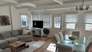 Ett modernt vardagsrum med en soffa, ett soffbord, en TV och ett matbord i glas med stolar.