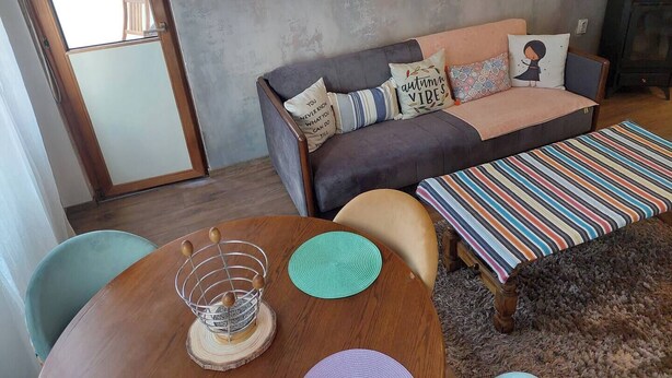 Ein gemütliches Wohnzimmer mit einer Couch, einem Esstisch und einem Bild an der Wand.