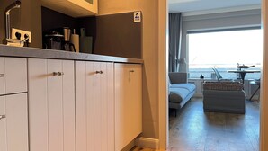 Ein Hotelzimmer mit einer Küchenzeile, einem Sofa, einem Esstisch und Meerblick.