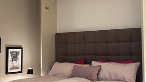Ein Schlafzimmer mit einem Bett, einer Kopfteil und einem gerahmten Bild an der Wand.