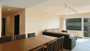 Un salon moderne comprenant une table à manger, des chaises, un canapé et une grande fenêtre donnant sur un beau paysage.