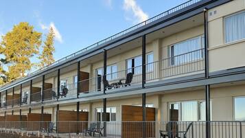 A multi-story residential building with balconies, large windows, and a clear sky.