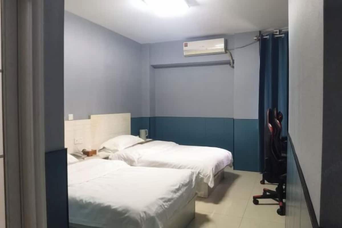 Camera d'albergo con due letti, una scrivania, un condizionatore d'aria e una sedia.