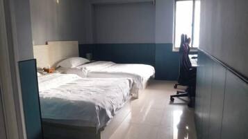Une chambre d’hôtel avec deux lits, un bureau et une chaise.