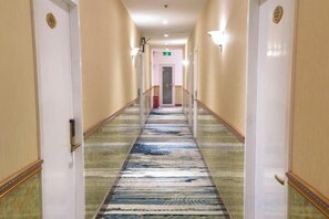 A hotel corridor with a carpeted floor, doors on either side, and a light fixture on the wall. - 211 E-sports Hotel (Shanghai Anting) (Shanghai)