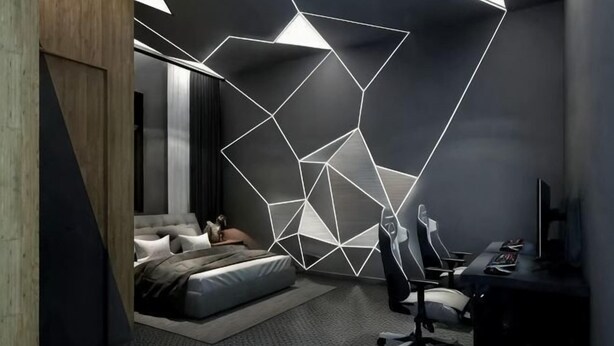 Een moderne slaapkamer met een geometrische lichtinstallatie, een bed, een bureau en een stoel.