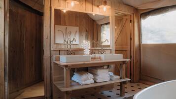 Ein Badezimmer aus Holz mit zwei Waschbecken, einem Spiegel und einem Ablagefach mit Handtüchern.