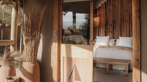 A wooden interior with a bed, a bench, and potted plants. - UNAI Atacama Luxury Tents (San Pedro de Atacama)