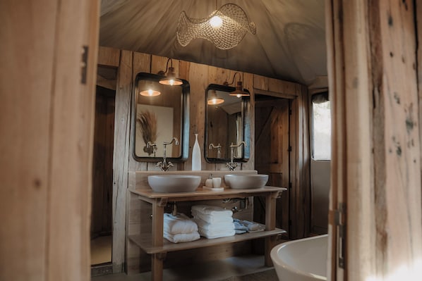 Une salle de bain en bois avec deux lavabos, un grand miroir et une baignoire.