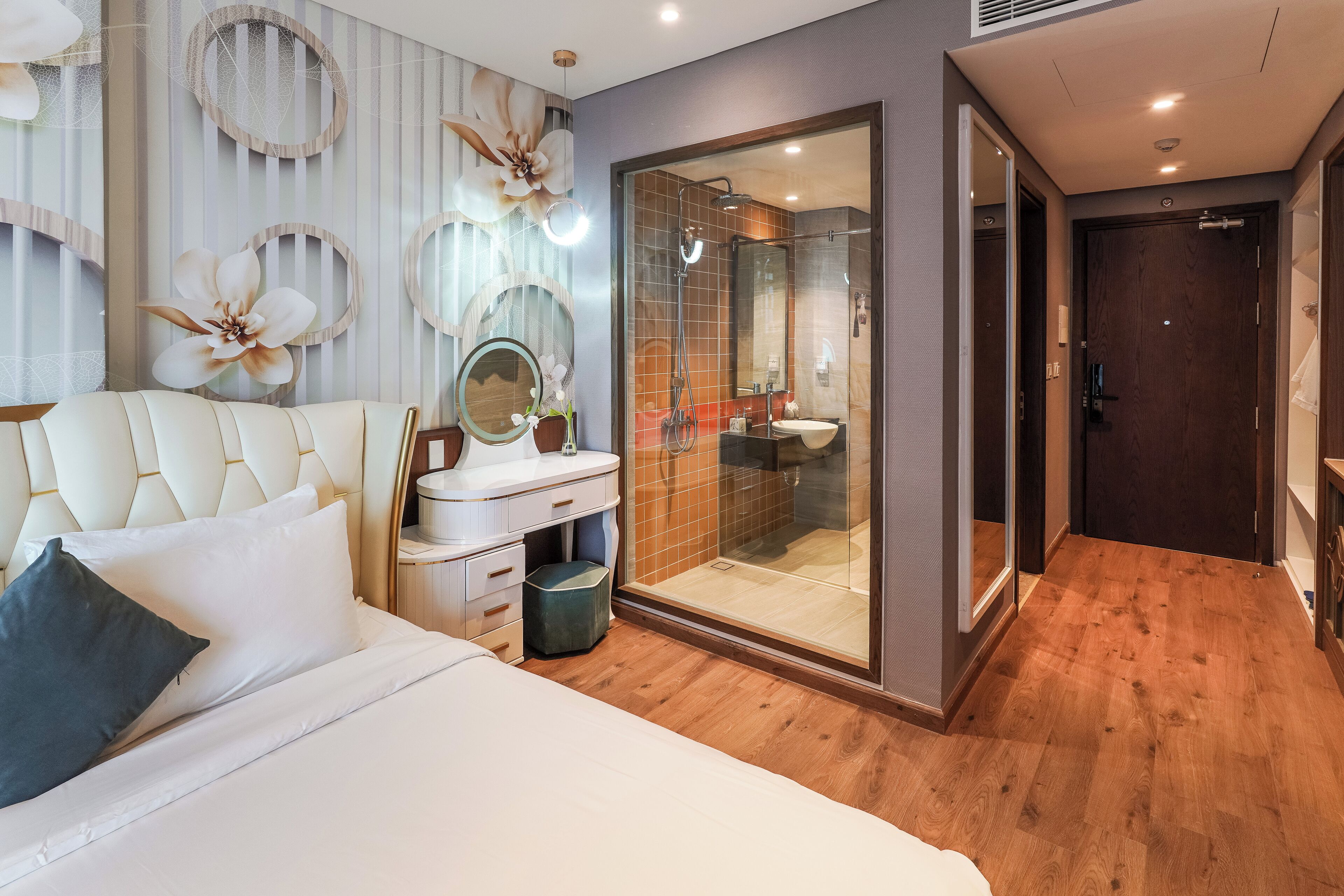 Un dormitorio moderno con una cama grande, un tocador con espejo y cabina de ducha con vidrio.