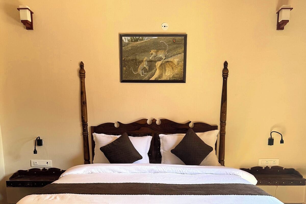 A four-poster bed with a dark wooden frame, white bedding, and two nightstands with lamps. A framed picture hangs above the bed.