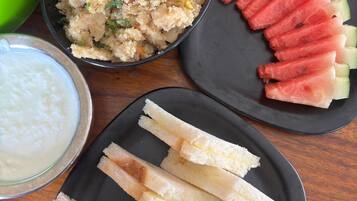 Une table avec un saladier de salade de couscous, des tranches de pastèque, une assiette de gressins et un bol de yaourt.