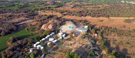Vista aérea de una propiedad rural con varias construcciones, incluyendo una casa grande con piscina, varias estructuras más pequeñas y una zona vallada.