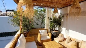 A covered outdoor seating area with wicker furniture and hanging lamps.