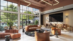 Un hall d’entrée spacieux doté de grandes fenêtres, un espace de détente central avec des canapés et des fauteuils, et un design moderne agrémenté d’un grand écran mural.