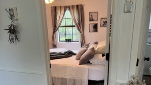Une chambre à coucher avec un lit, des rideaux, une fenêtre et une porte.