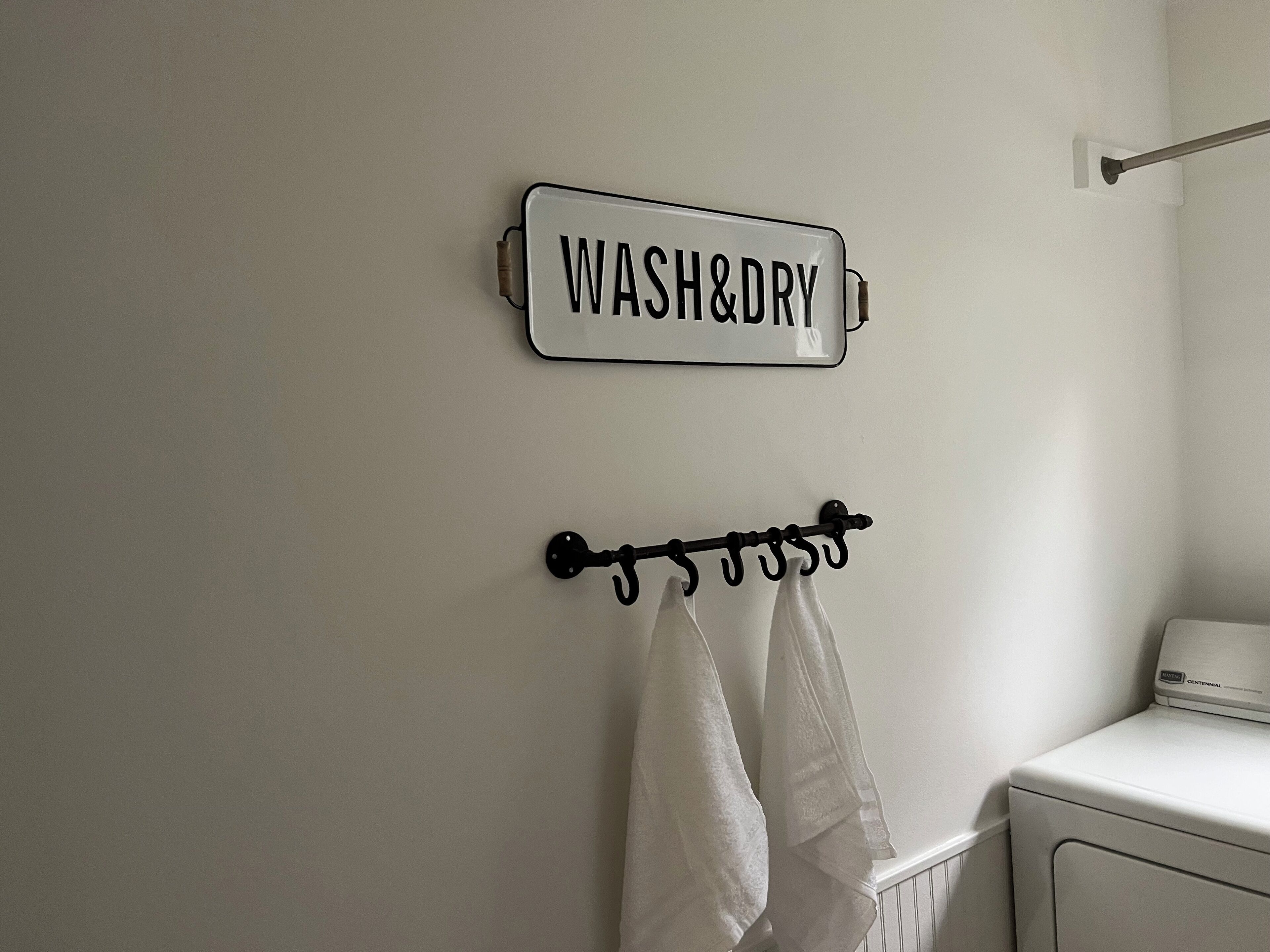 A bathroom with a 'WASH&DRY' sign and a towel rack with towels.