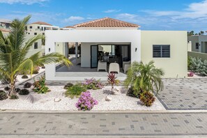 Una casa moderna con un patio, paredes blancas y techo de tejas.