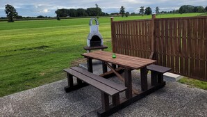 A picnic area with a stone grill and wooden benches. - Vacation apartment with garden in Drochtersen (Drochtersen)