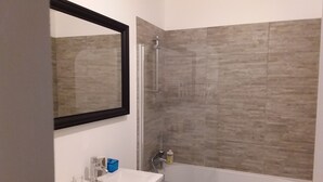 A bathroom with a white sink, a mirror, a shower with a glass door, and a bathtub.