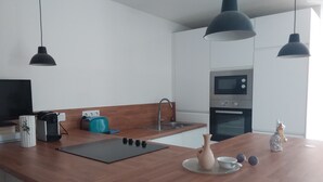 A modern kitchen with wooden countertops, a built-in oven, a sink, and pendant lighting.