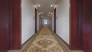 A long, narrow hallway with patterned carpet and wooden doors on both sides. - Vienna 3 Best Hotel (Beijing)