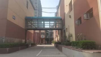 A building entrance with a covered walkway, a sign indicating a parking area, and a clear sky.