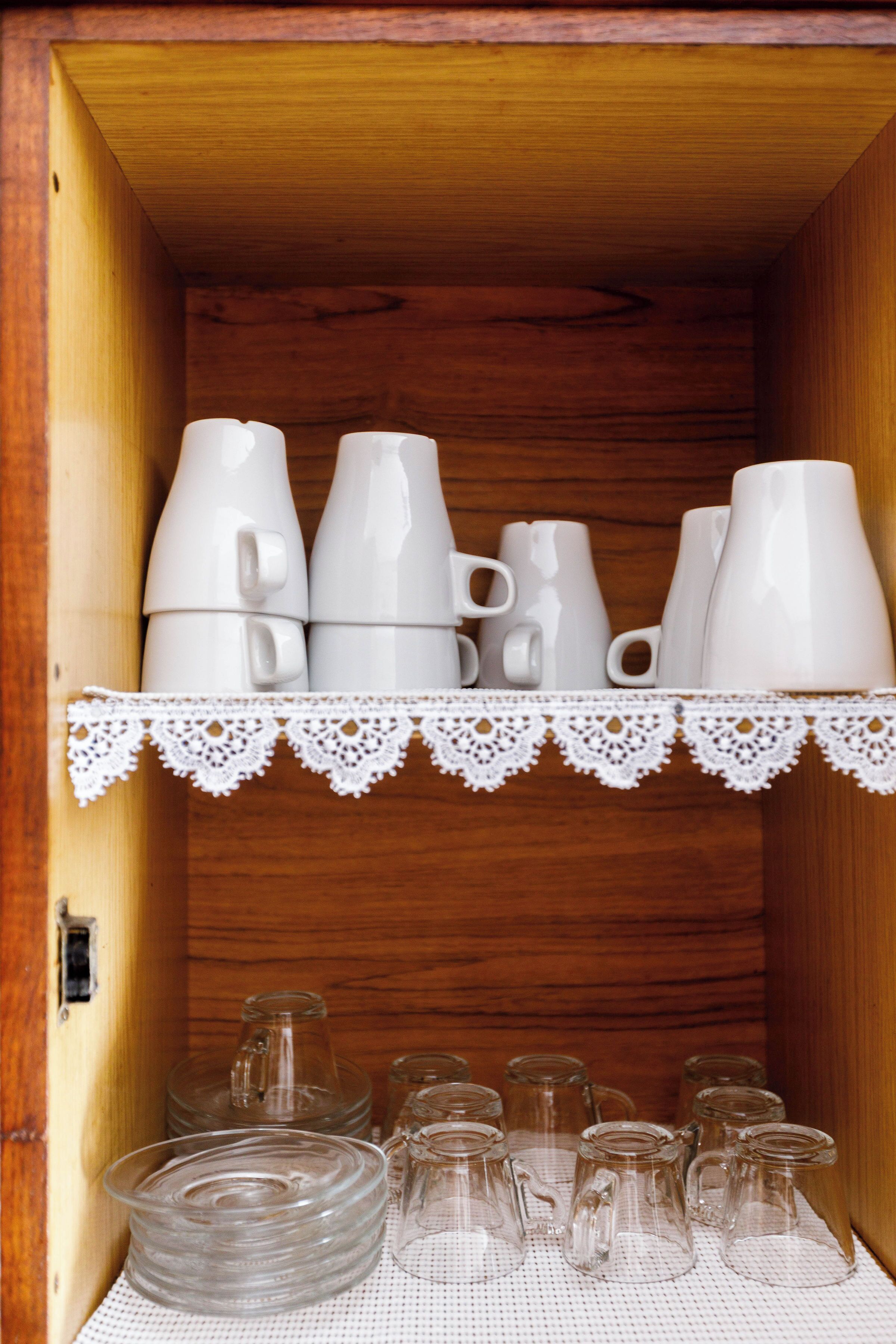 Un meuble en bois contenant des tasses et des verres en céramique blanche.