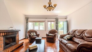 Una sala de estar con chimenea, sofás de cuero, una mesa de centro y una araña.