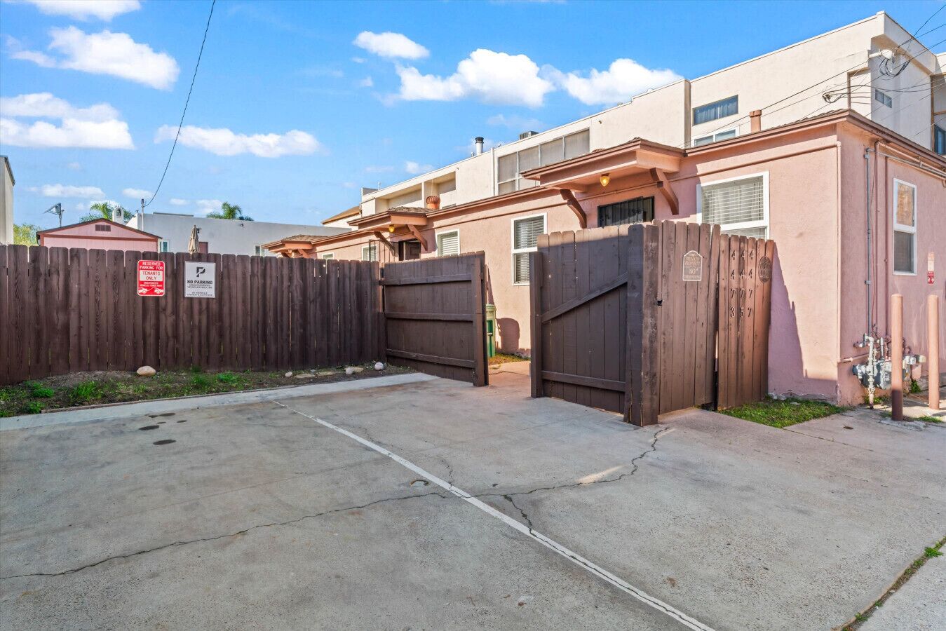 A gated residential area with a concrete driveway leading to a building with multiple windows and a flat roof.