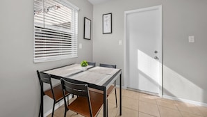 A dining area with a table, chairs, a potted plant, and a door.