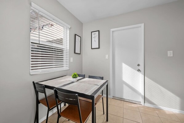A dining area with a table, chairs, a potted plant, and a door.