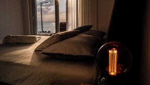 Un dormitorio con un ventanal grande, una cama con almohadas y una lámpara de estilo vintage.