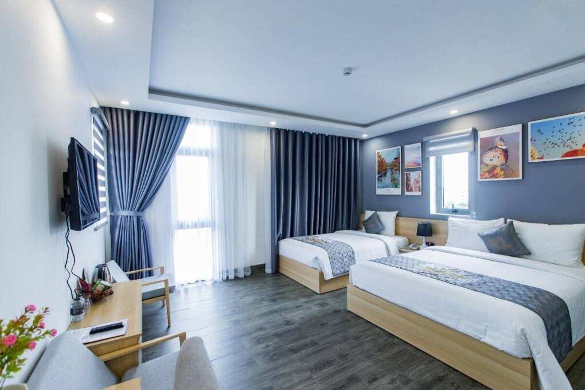 Una habitación de hotel moderna con dos camas, un escritorio y una televisión.